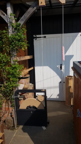 Hoem Dumbbell setup in farmhopuse porch, with floor standing dumbbell and ropes ascending to pullies on rafters.